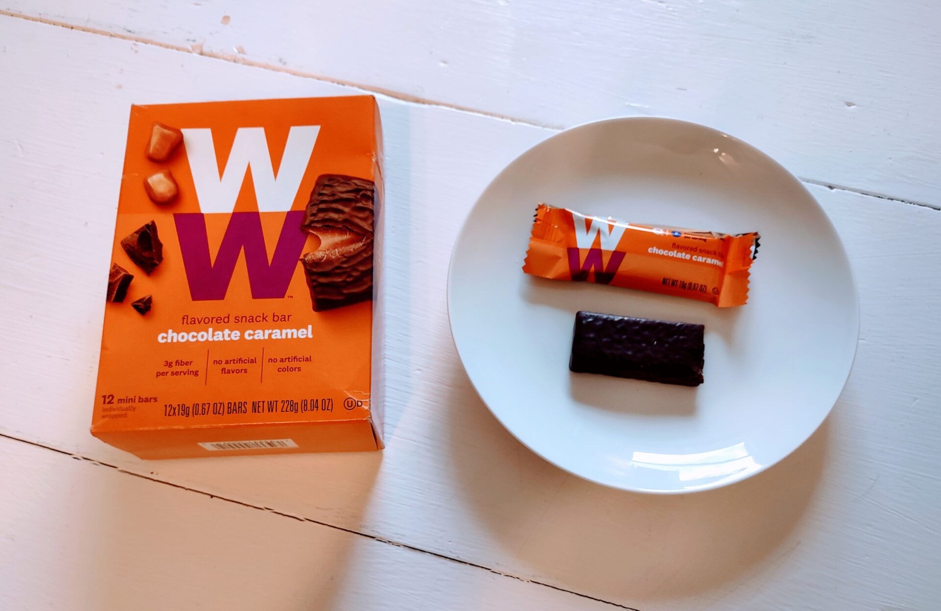 A box and one bar of WeightWatchers Chocolate Caramel Mini Bars on a table.