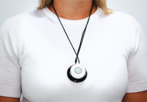 A person in a white shirt wearing a Bella Charm necklace flipped over to show the help button necklace.