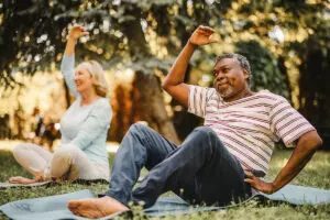 Black senior doing relaxation exercises during physical therapy class in nature.