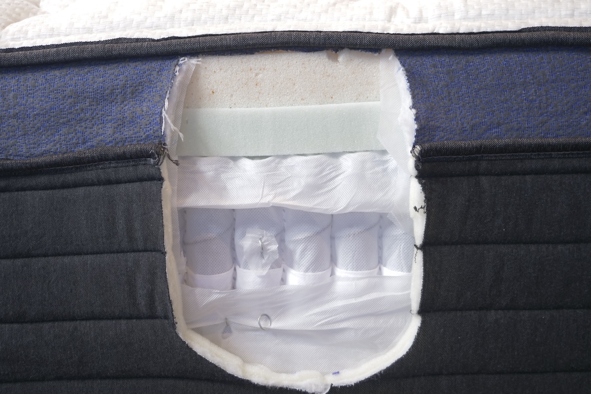 A hole cut out showing layers of Helix Midnight Luxe mattress.