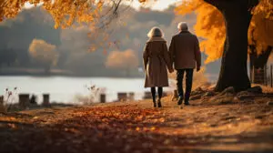 Couple holding hands and walking by a lake during fall