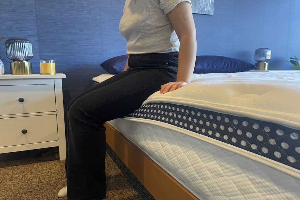 Our tester sitting down on The WinkBed mattress to test firmness