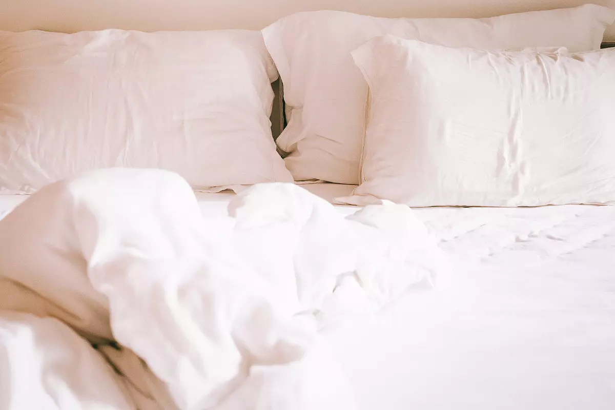 Rumpled white pillows and sheets on a bed