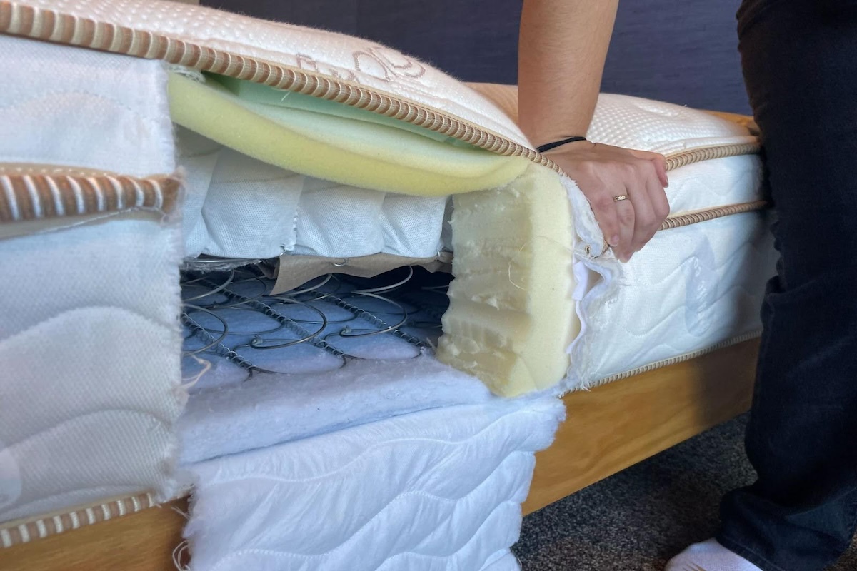  A person presses on a cut-out Saatva Classic mattress.