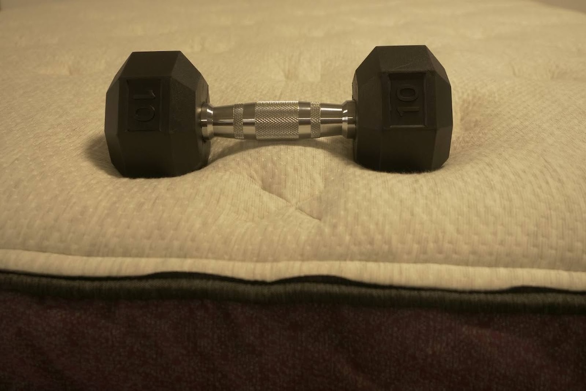 A 10-pound dumbbell sits on the Helix Dusk Luxe mattress.