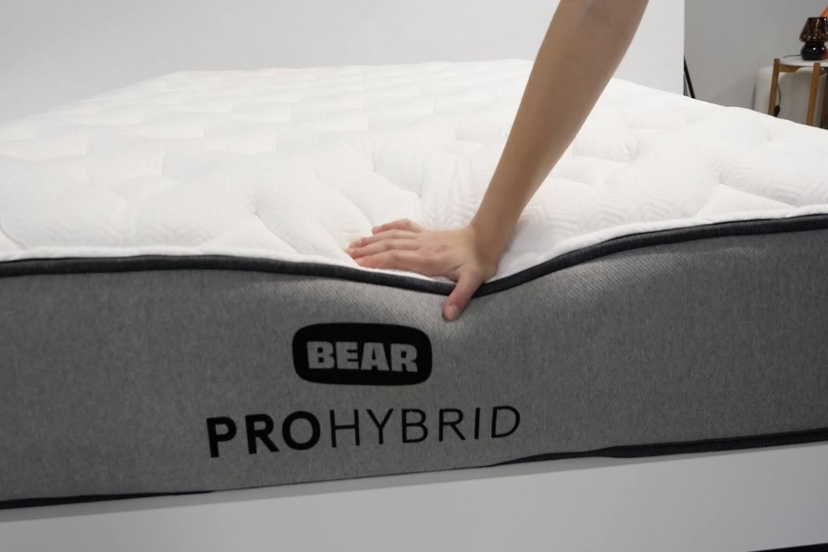 A hand pushing on the edge of the Bear Pro Hybrid. 