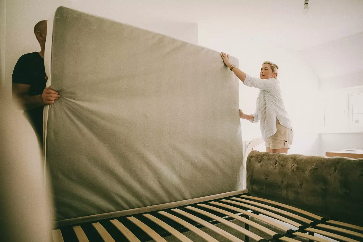 A man and woman installing a mattress on a bed foundation