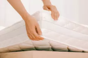 Hands lifting the corner of a mattress up
