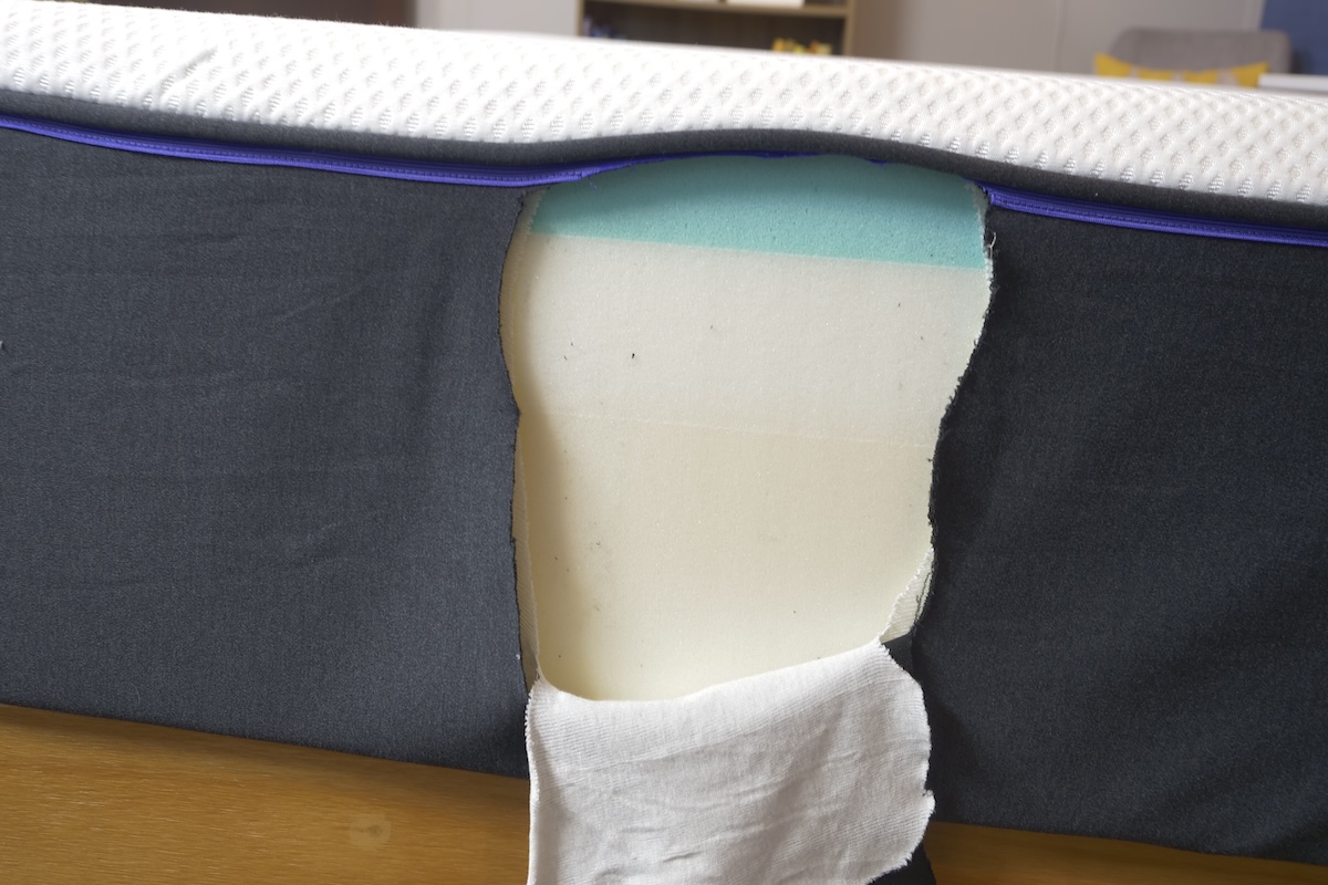 A Nectar Premier Copper mattress that has been cut open to reveal the layers of materials inside shows a white memory foam layer with a blue therapeutic gel foam layered on top of it
