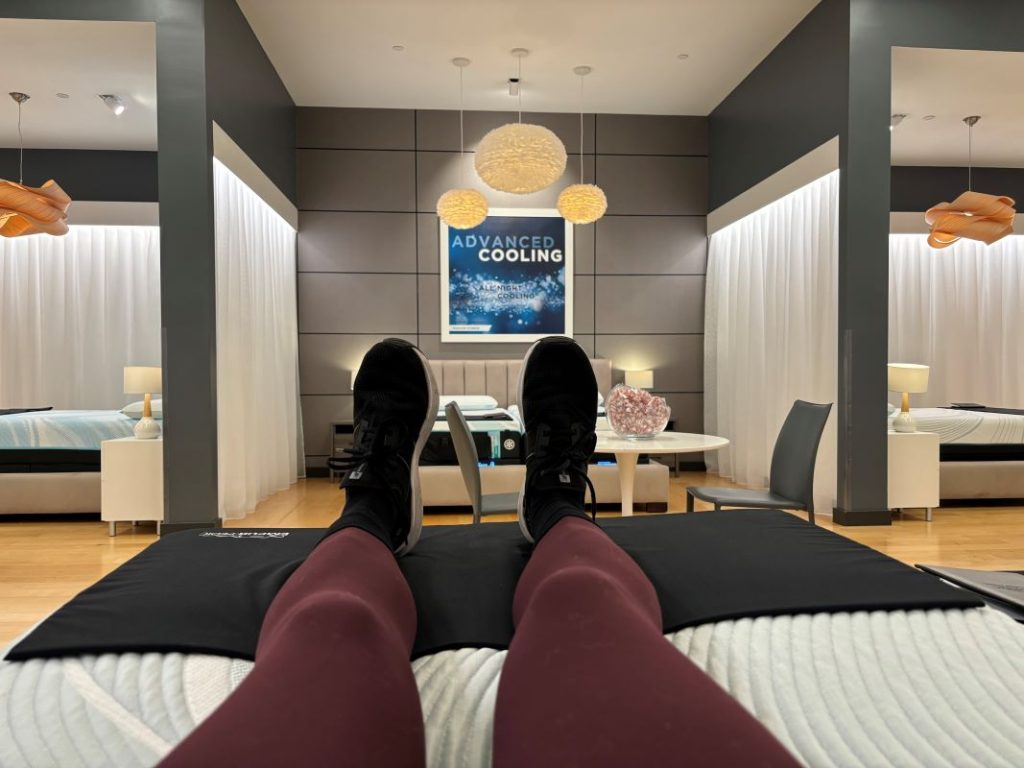 Picture of the legs and feet of a mattress tester laying on a mattress