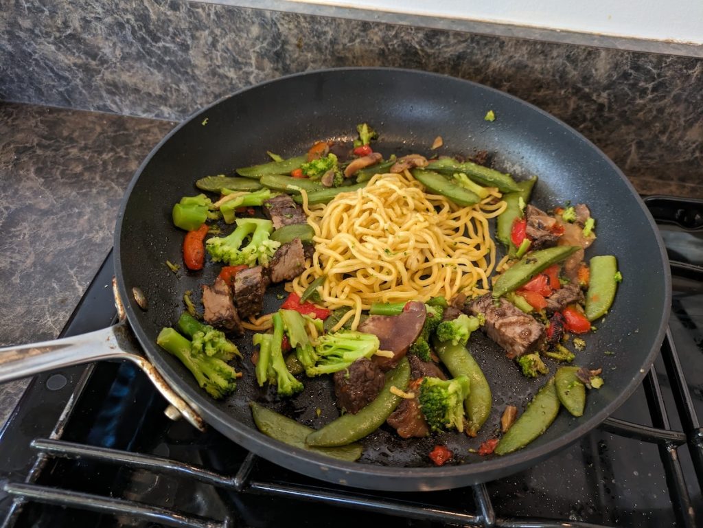 Beef lo mein cooking on a pan
