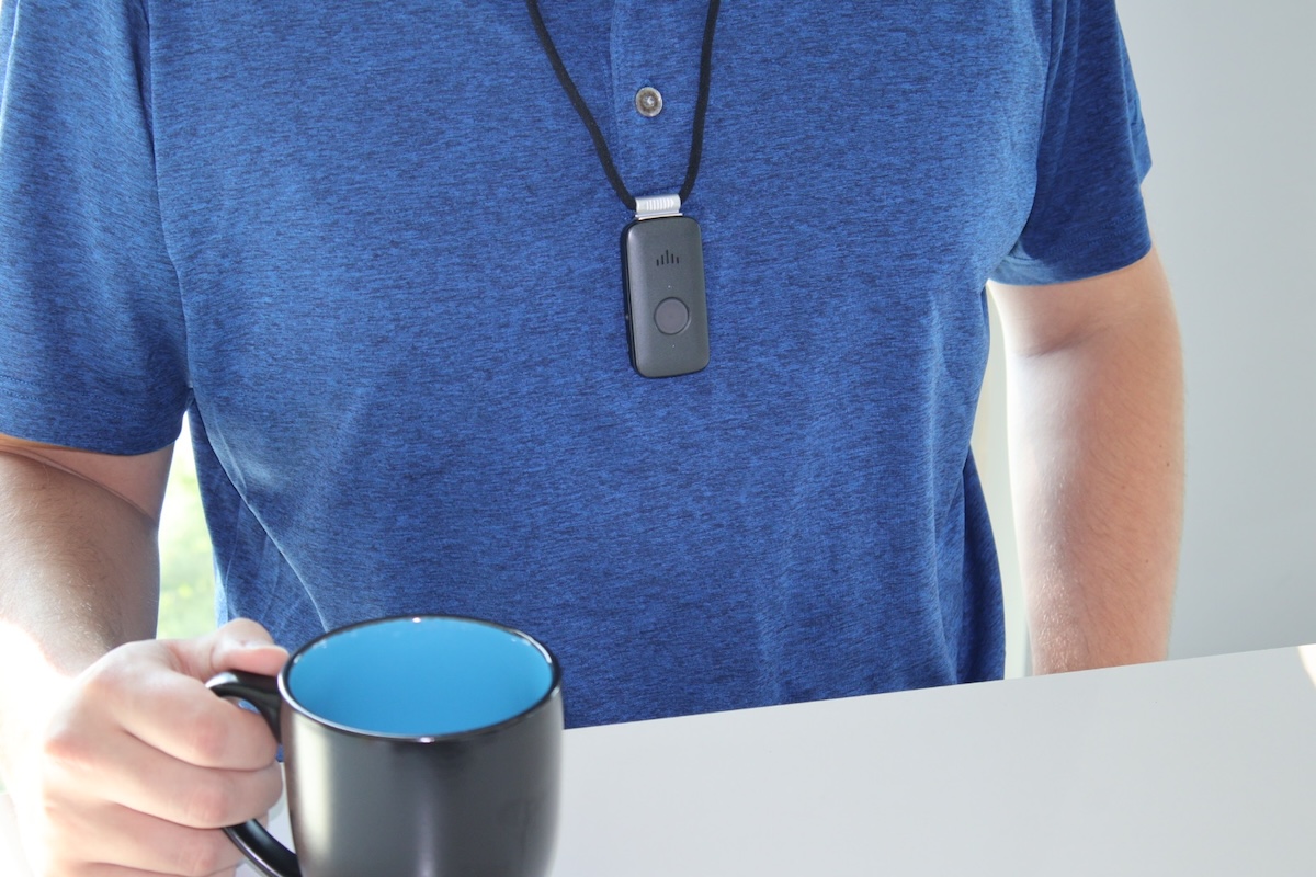 Man wears the SOS Mobile around his neck on a lanyard while holding a coffee mug in one hand