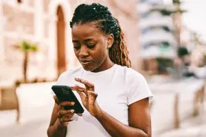 Woman on sidewalk engaging with her smartphone.