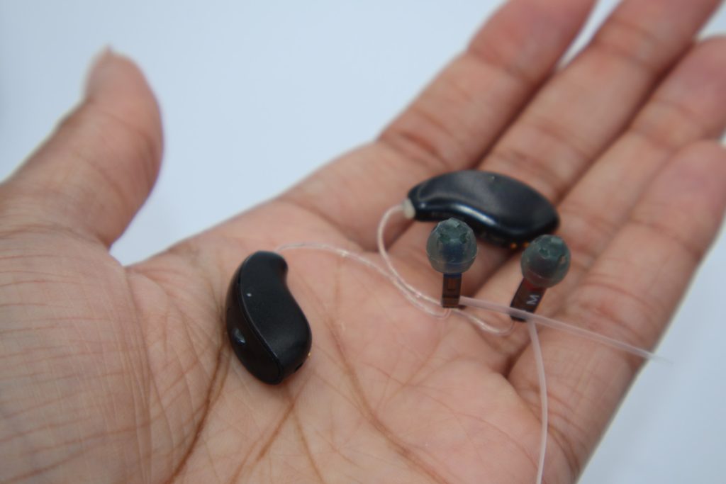 Starkey Genesis AI hearing aids rest behind the ear, and are waterproof up to one meter depth.