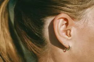 woman wears a discreet hearing aid in her right ear