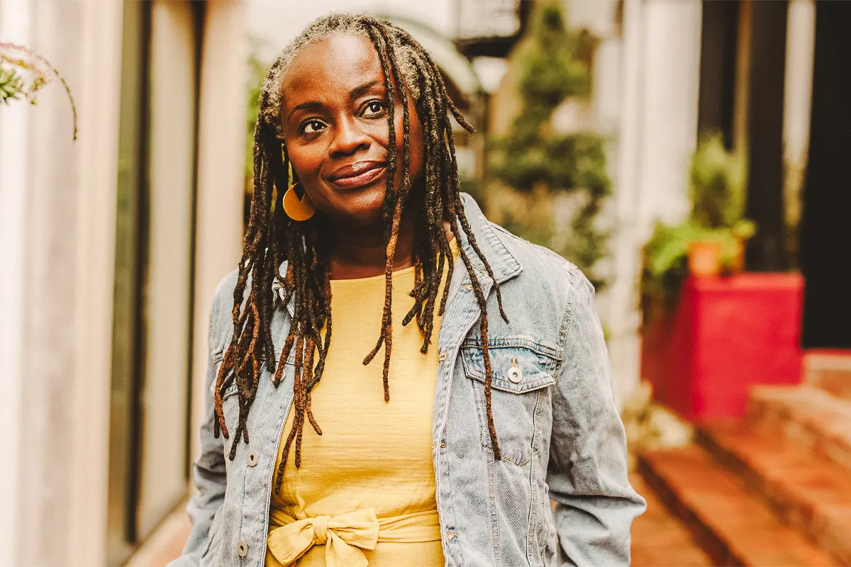 Black woman smiles and stares into the distance on a city street